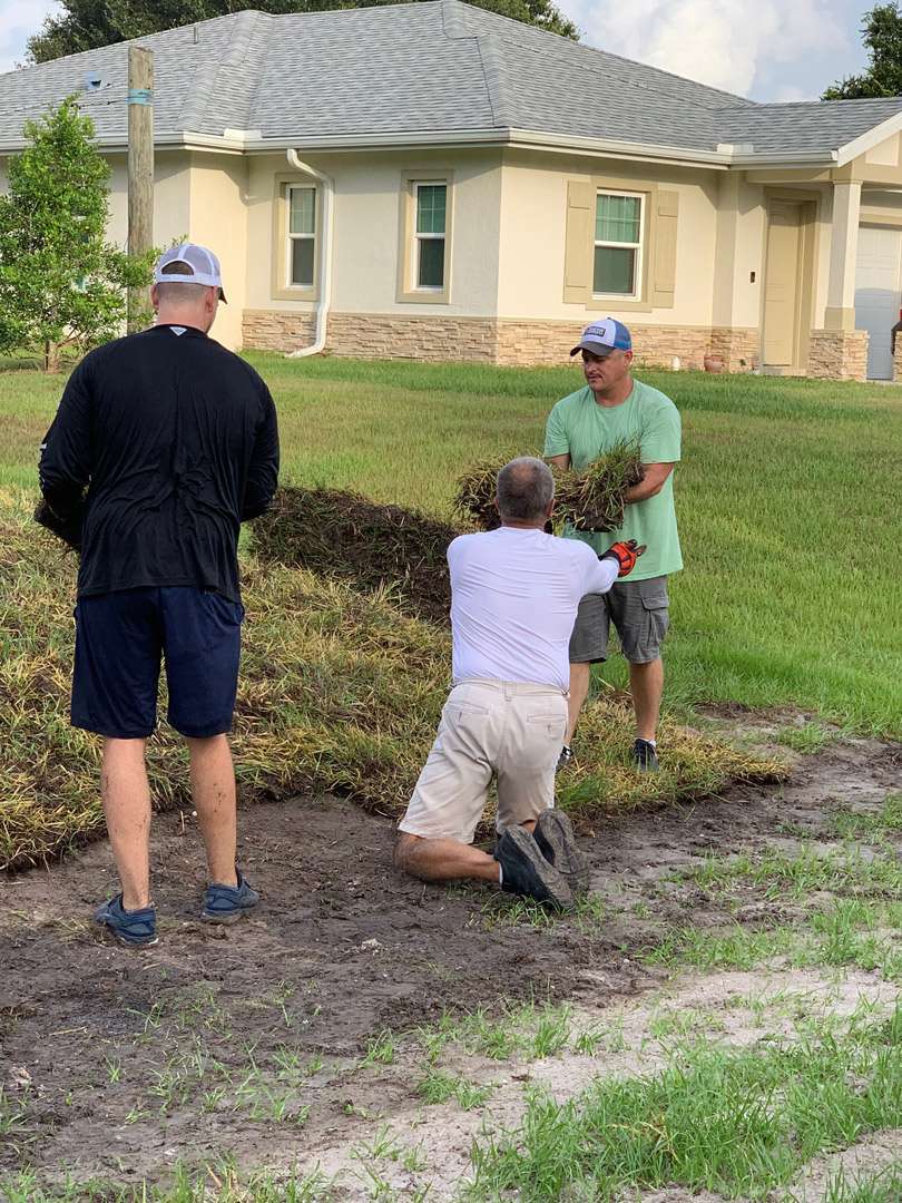 a group of men standing on a dirt mound in front of a house